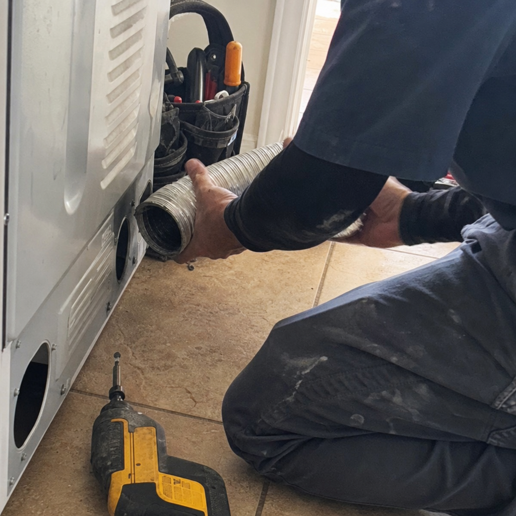Technician connecting flexible hose to dryer for vent cleaning service