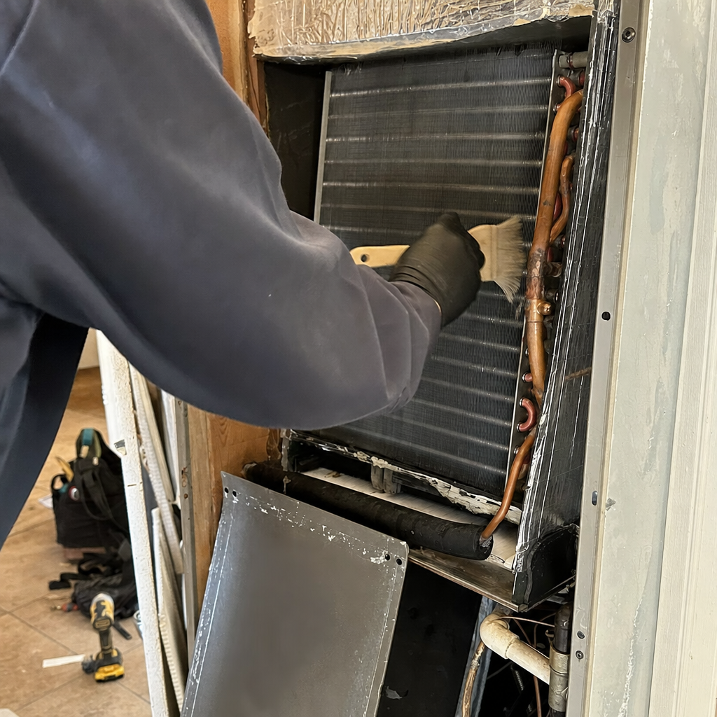HVAC technician cleaning evaporator coils of an air conditioning unit